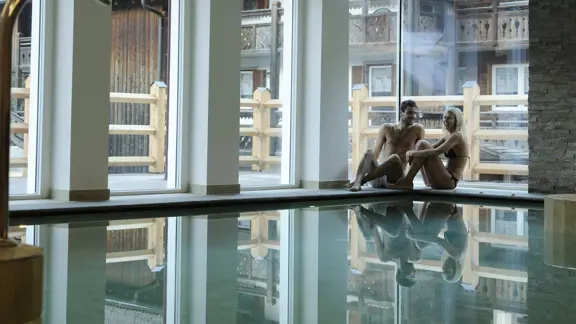 A couple sitting together by the edge of a swimming pool at the hotel