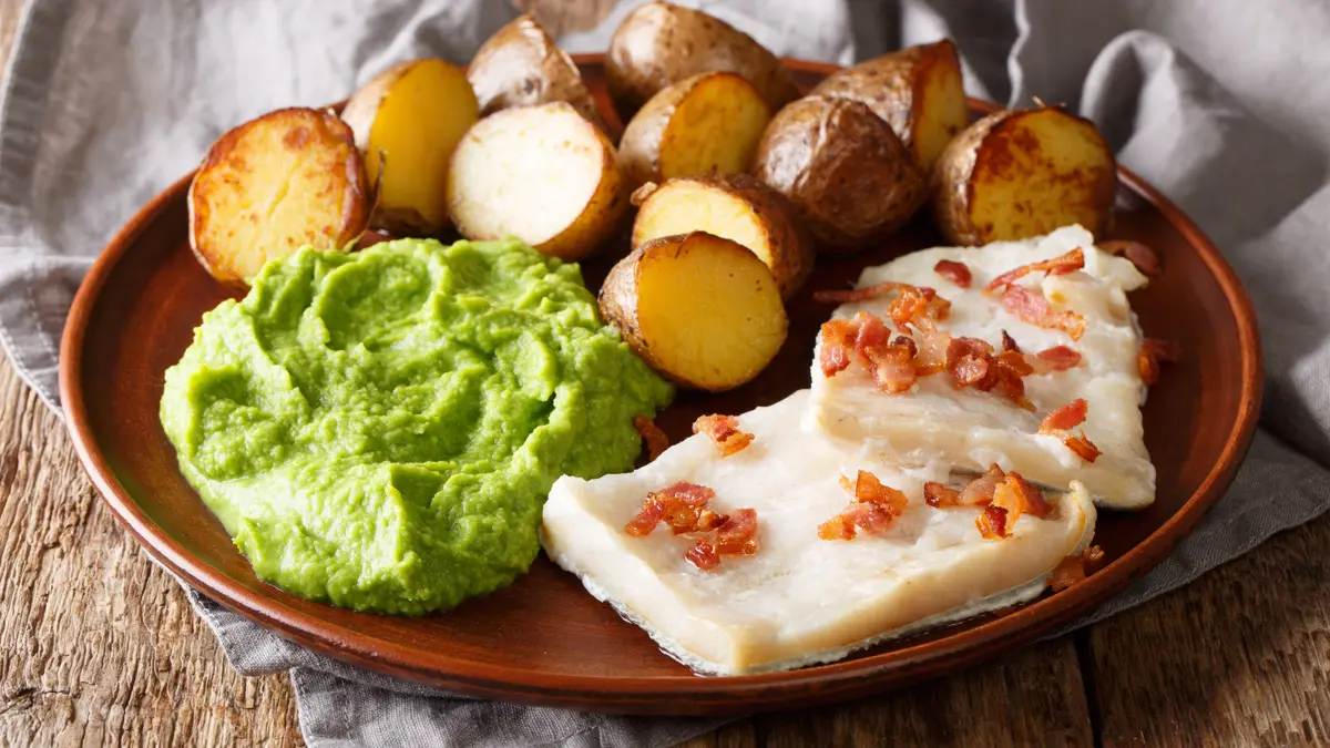 Lutefisk Served With Pea Puree, Potatoes And Bacon Close Up